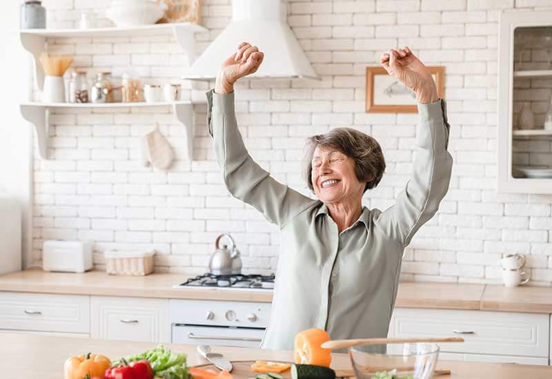 Woman in the kitchen stretching and smiling