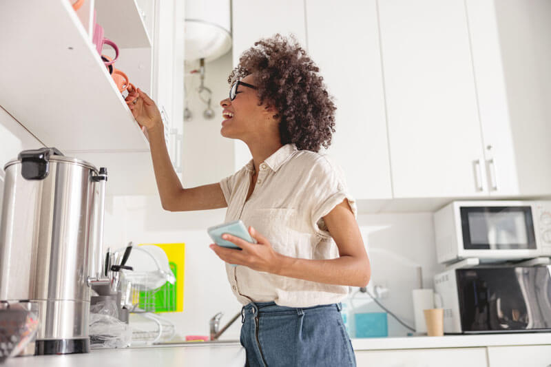 Woman reaching for something in the kitchen and smiling