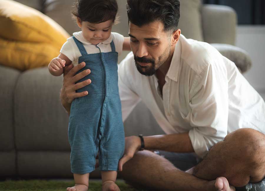 father holding child up to help walk