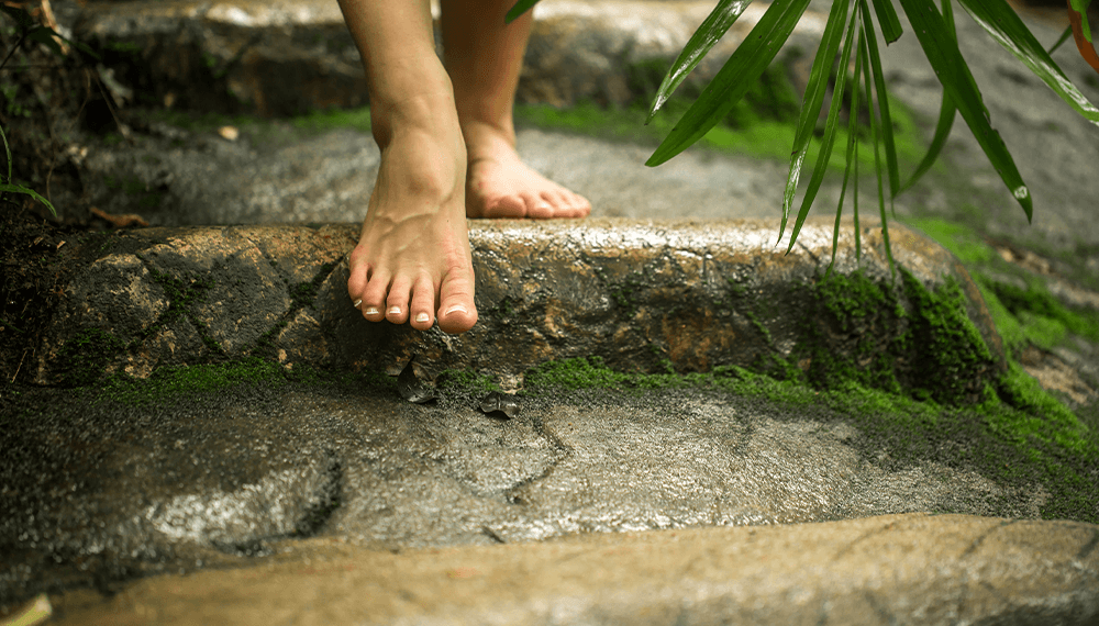 bare feet taking a step down stone steps out in nature