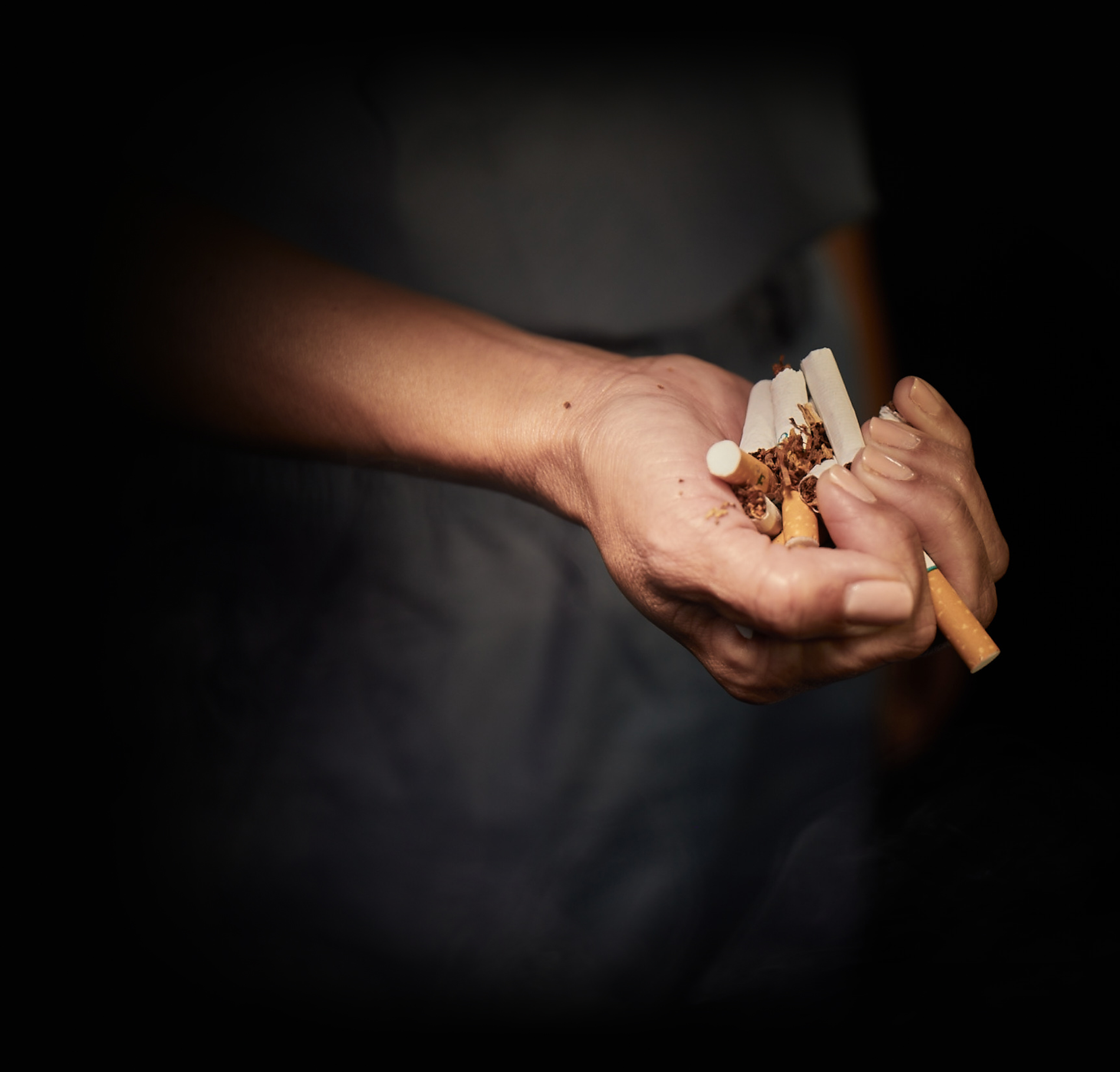 A partially closed hand full of 6 crumbled cigarettes